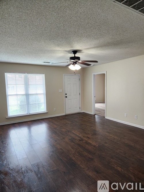 A room with a ceiling fan and wooden flooring.