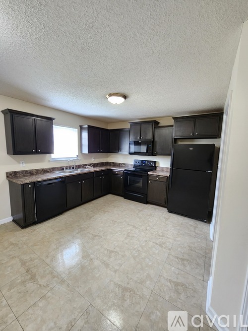 A kitchen with black cabinets and appliances.