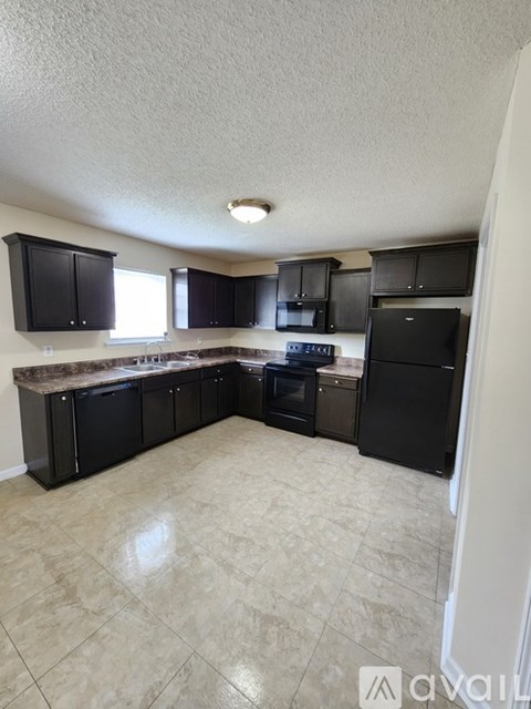 A kitchen with black cabinets and appliances.