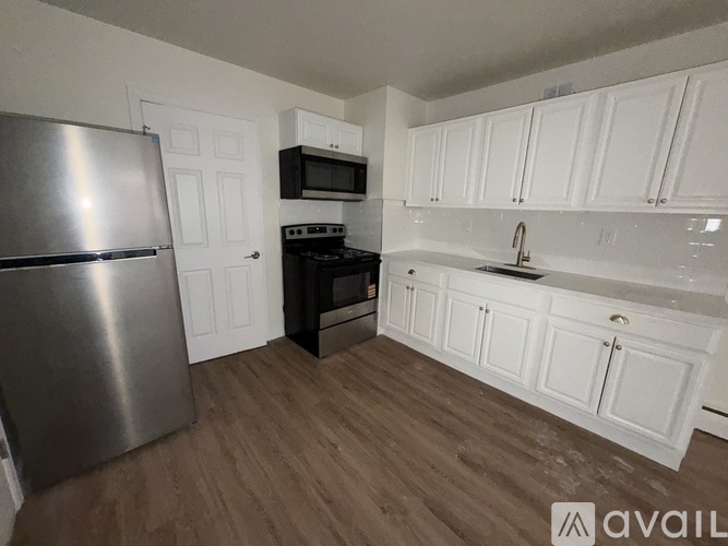 A kitchen with white cabinets and a stainless steel refrigerator.