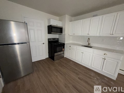 A kitchen with white cabinets and a stainless steel refrigerator.