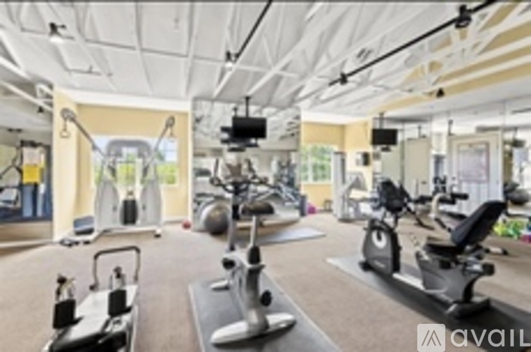A gym with a variety of exercise equipment including treadmills, stationary bikes, and elliptical machines.
