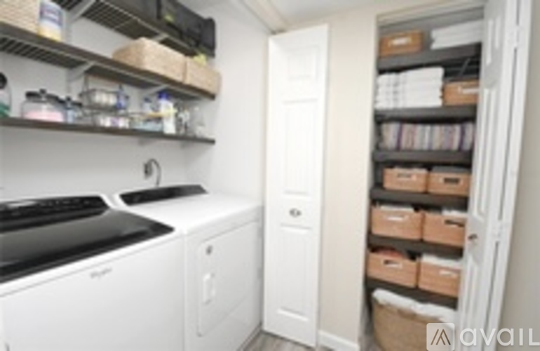 A small kitchen with a washing machine and a cabinet full of boxes.