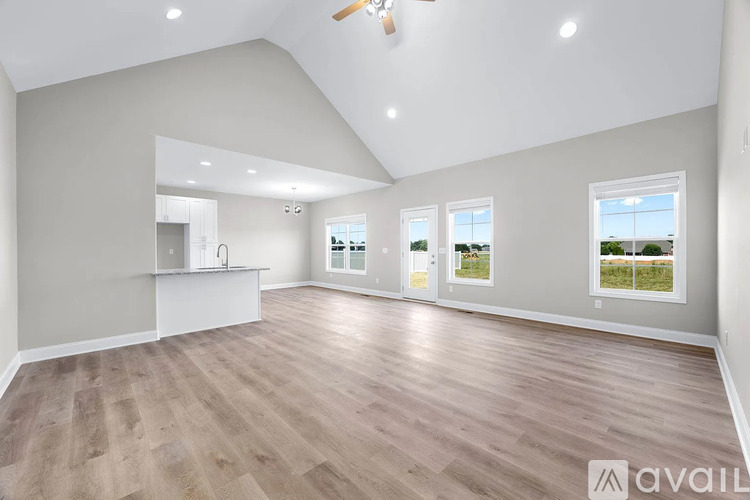 A spacious room with wooden flooring and a ceiling fan.