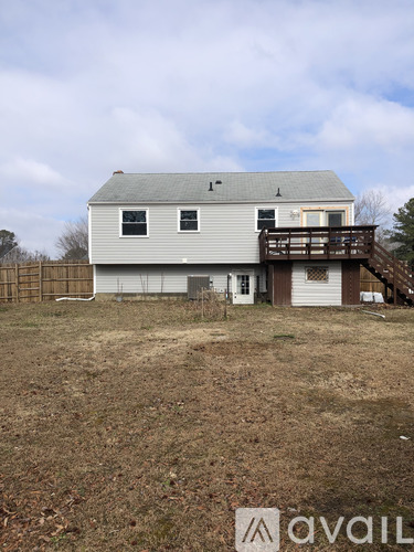 A house with a grey roof and a deck in the backyard.