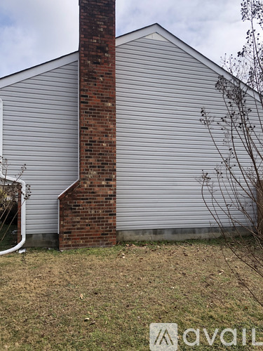 A house with a grey siding and a red brick chimney.