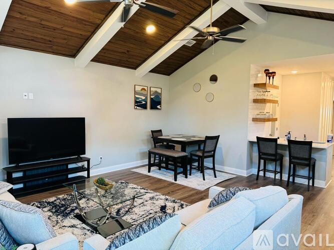 A living room with a television, a table, and chairs.