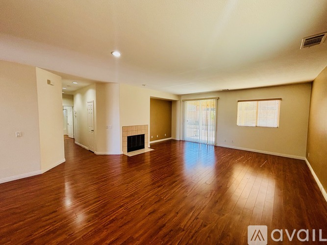 A spacious room with wooden flooring and a fireplace.