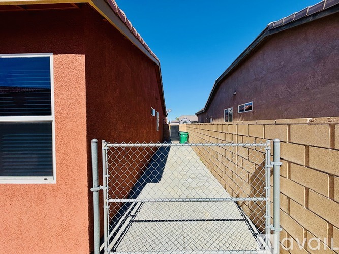 A metal fence separates two buildings.