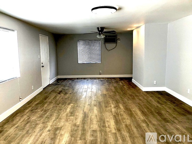 A room with wooden flooring and a flat screen TV mounted on the wall.