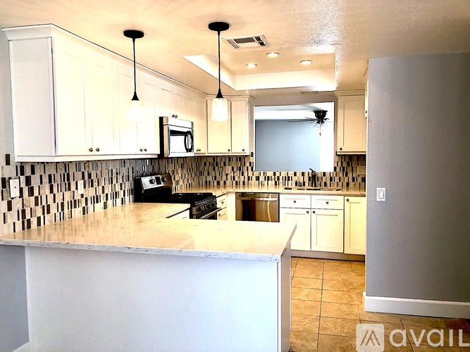 A kitchen with white cabinets and a checkered backsplash.