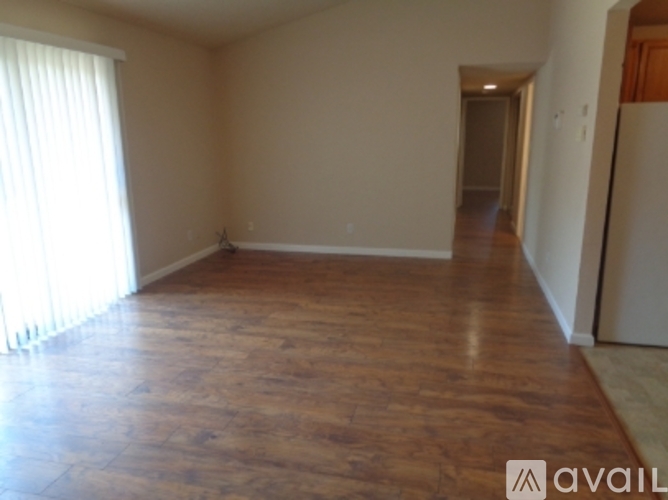 A room with wooden flooring and a window on the left side.