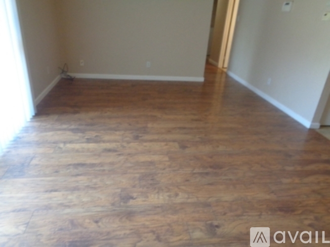 A room with wooden flooring and a door on the right side.
