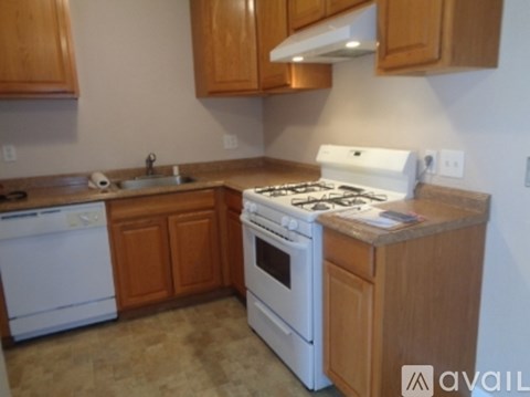 A kitchen with a white stove top oven and white dishwasher.