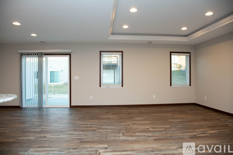 A spacious room with wooden floors and two windows.