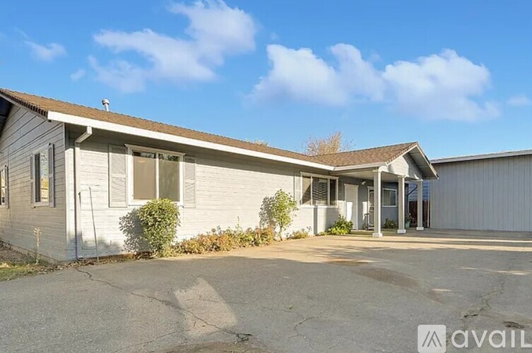 A house with a grey roof and white walls is available for rent.