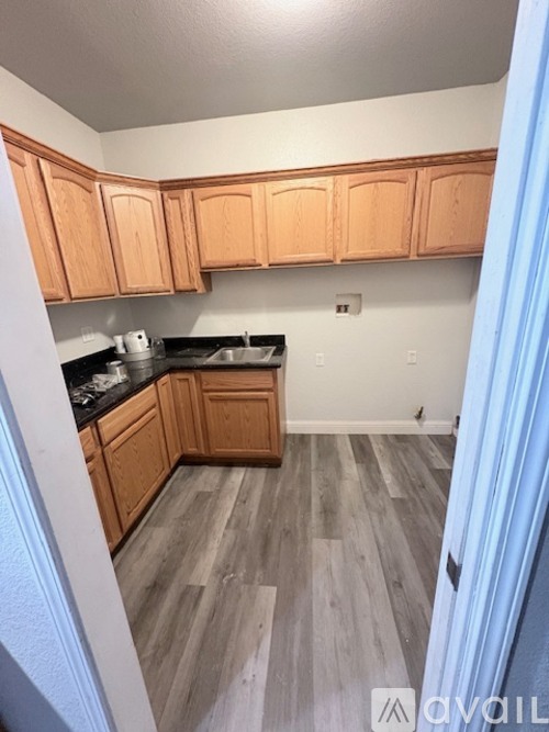 A kitchen with wooden cabinets and a grey floor.