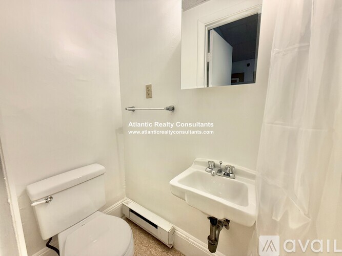 A white bathroom with a toilet, sink, and mirror.