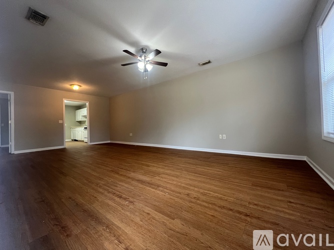 A spacious room with wooden flooring and a ceiling fan.