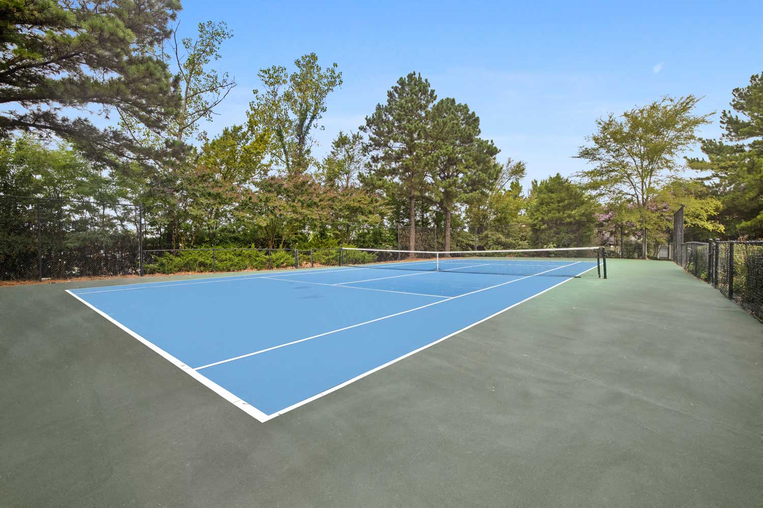 Apartment tennis court surrounded by shade trees for residents of Cordova apartments for rent