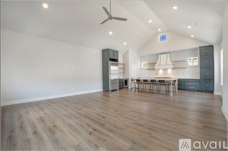 A spacious room with a wooden floor and a ceiling fan.