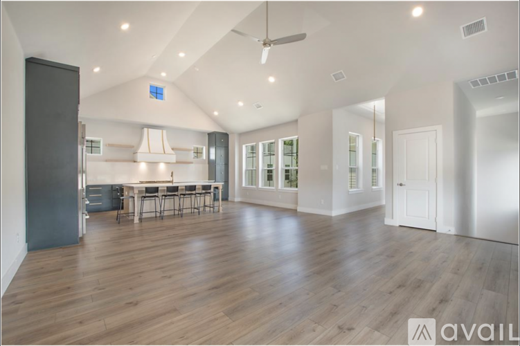 A spacious room with wooden flooring and a dining area with a table and chairs.