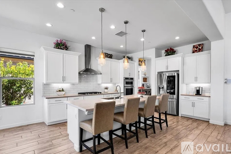 A modern kitchen with a large island and chairs.