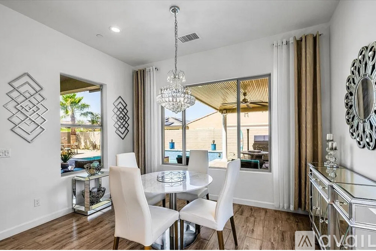 A modern dining room with a glass table and white chairs.