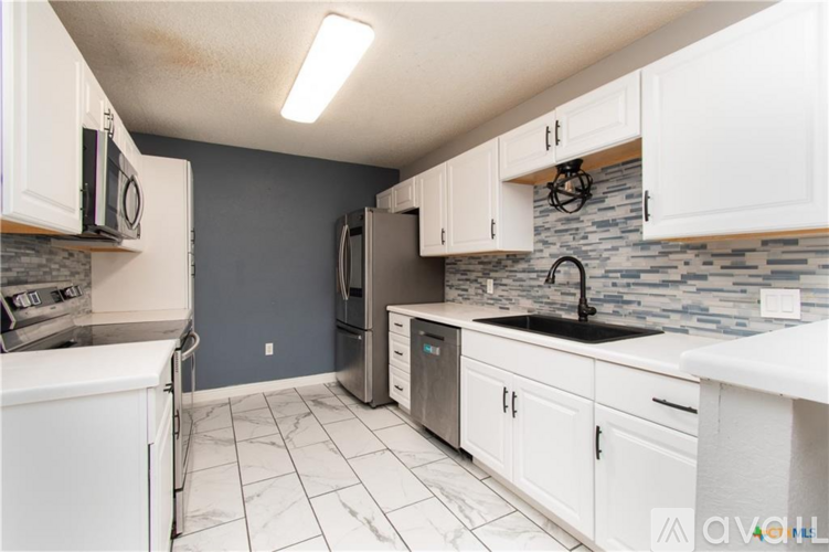 A kitchen with white cabinets and a black faucet.