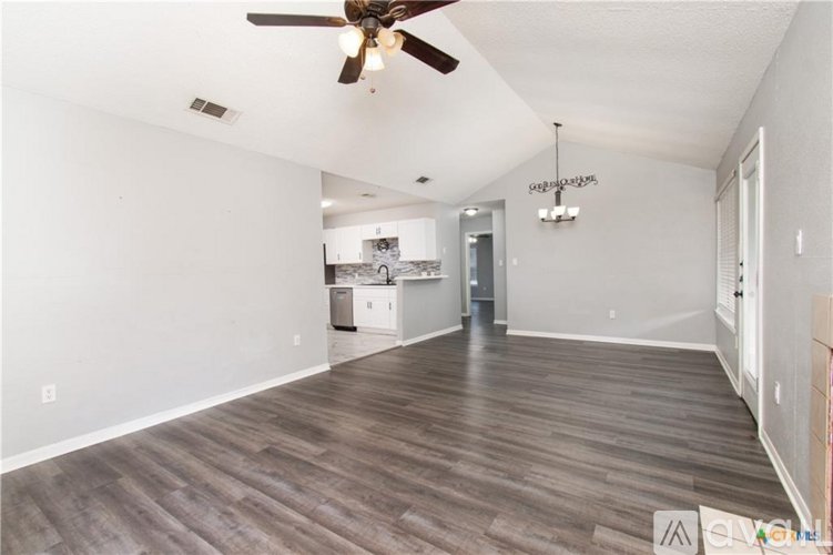 A spacious room with a ceiling fan and wooden flooring.