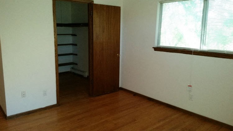 an empty room with a wooden floor and a closet