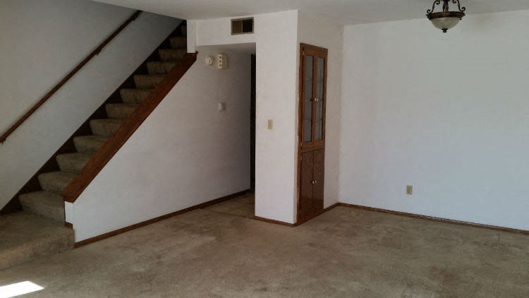 an empty living room with stairs and a door