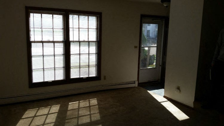 an empty living room with two windows and a door