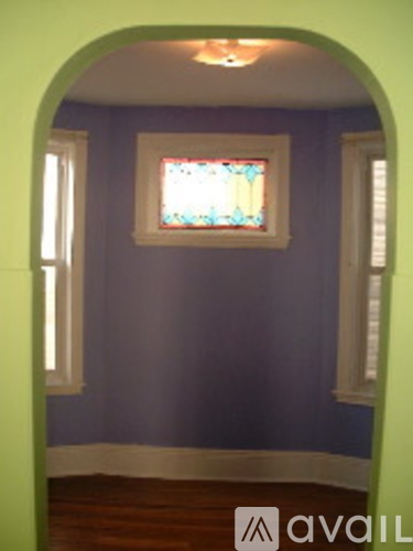 A room with a stained glass window and a green archway.