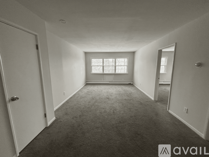A spacious room with a carpeted floor and a window with blinds.