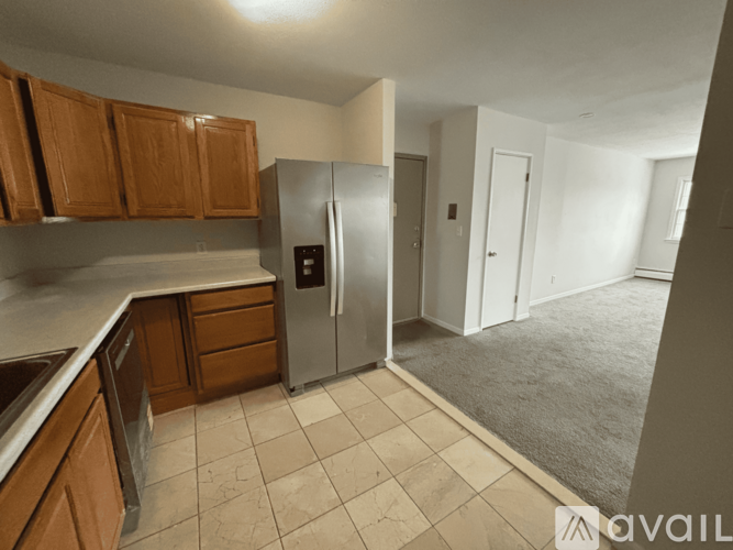A kitchen with wooden cabinets and a stainless steel refrigerator.