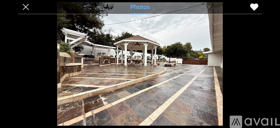 A gazebo is situated in the middle of a tiled courtyard.