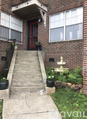 A red door is on the left side of a brick building.