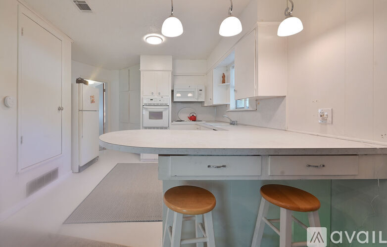 A kitchen with a white countertop and bar stools.