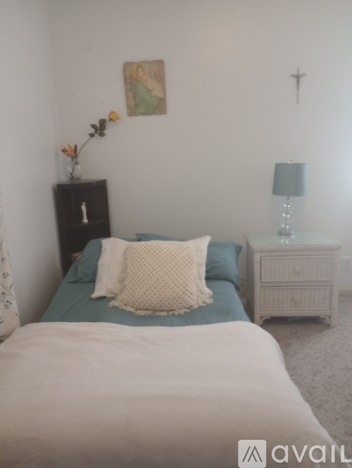 A bedroom with a bed, nightstand, and lamp.