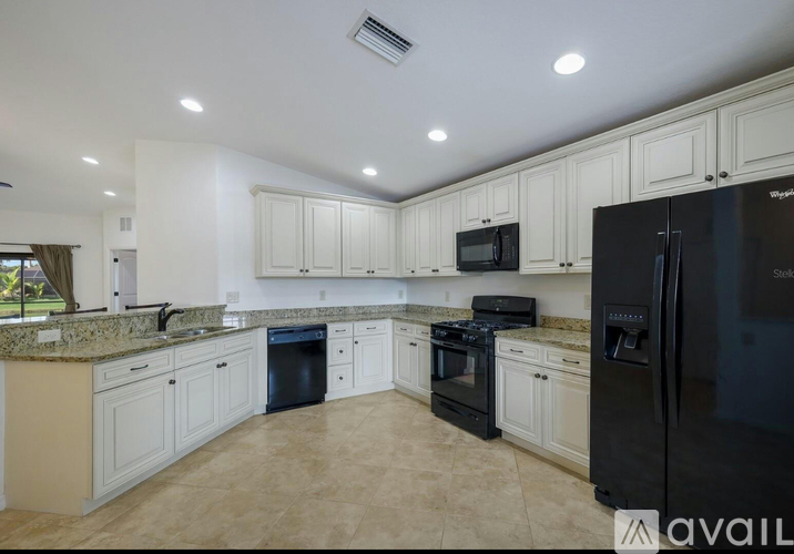 A kitchen with black appliances and white cabinets.