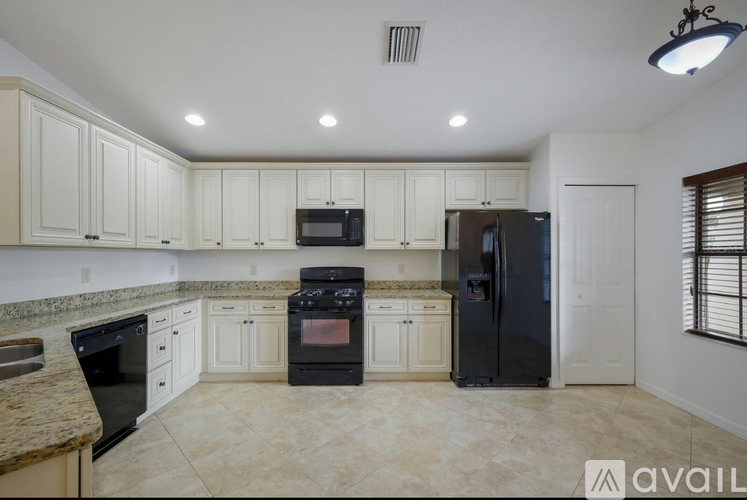 A kitchen with black appliances and white cabinets.