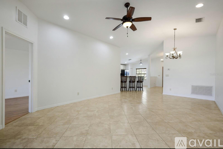 A spacious room with a ceiling fan and a chandelier.