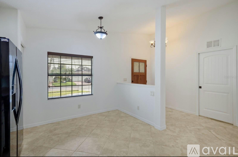 A room with a window, a door, and a fridge.
