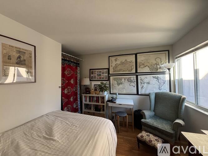 A bedroom with a bed, a chair, and a table with a lamp.