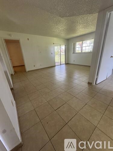 A spacious room with tiled flooring and a door on the left.