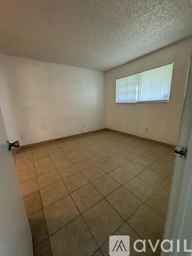 A room with beige tiled flooring and a window with blinds.