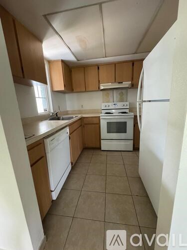 A kitchen with white appliances and wooden cabinets.