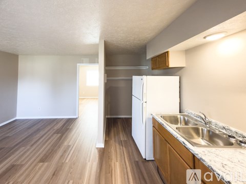 A kitchen with a white refrigerator and wooden floors.