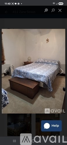 A bedroom with a bed and a wooden box on the floor.